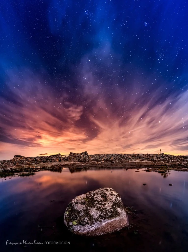 Atardecer estrellado sobre laguna con rocas musgo en paisaje montañoso de la Sierra de Francia