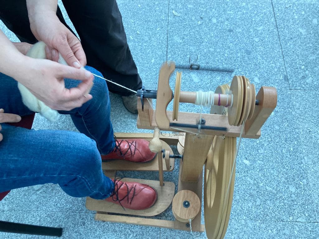 Persona demostrando técnica tradicional de hilado con rueca de madera artesanal en la Sierra de Francia.