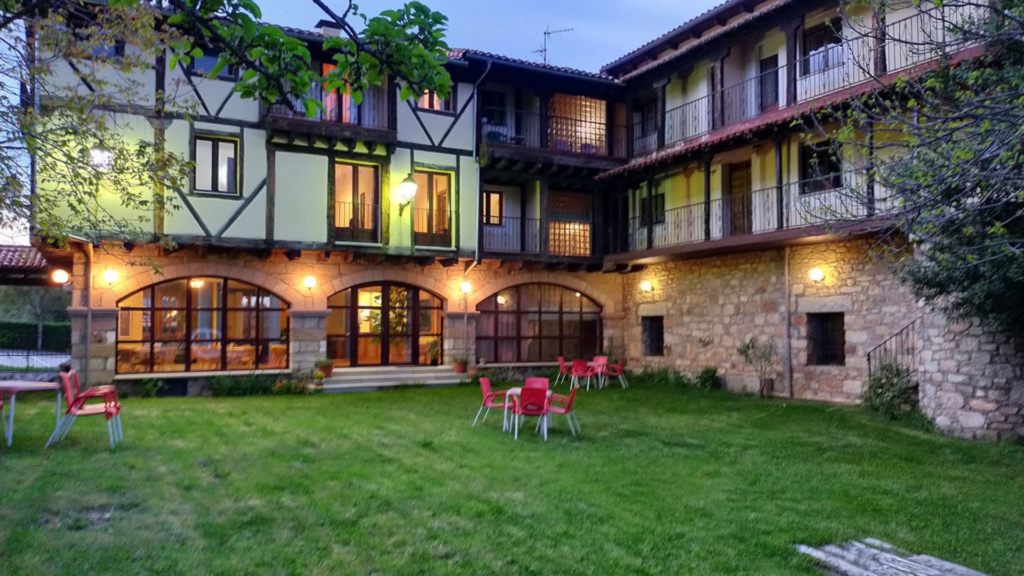 Patio interior del Hotel Antiguas Eras en la Sierra de Francia, con arquitectura tradicional, iluminación nocturna y sillas rojas.