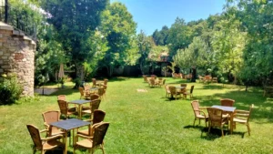 Jardín con mesas y sillas de mimbre bajo árboles frondosos en el Hotel Antiguas Eras, Sierra de Francia.