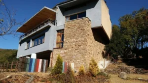 Casa de arquitectura moderna en la Sierra de Francia con fachada blanca, piedra natural y balcones de madera.