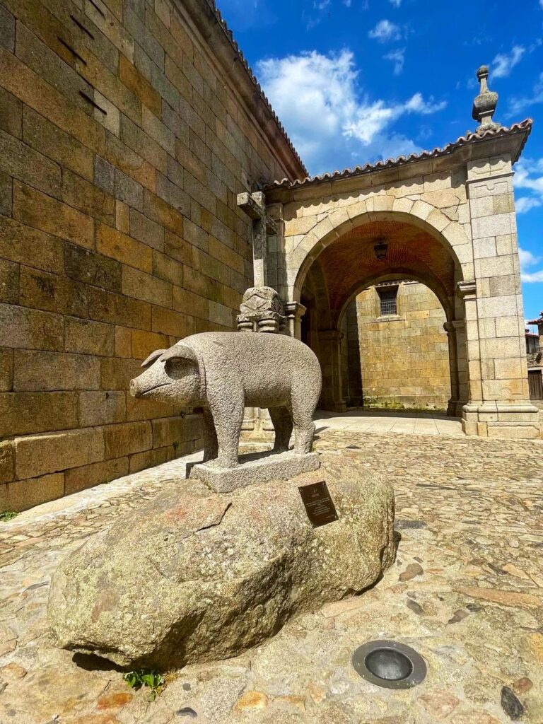 Escultura de verraco en piedra frente al arco medieval de La Alberca, Sierra de Francia