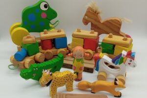 Juguetes de madera coloridos: rana, caballo, cocodrilo, leopardo, cometa y figuras geométricas apilables.