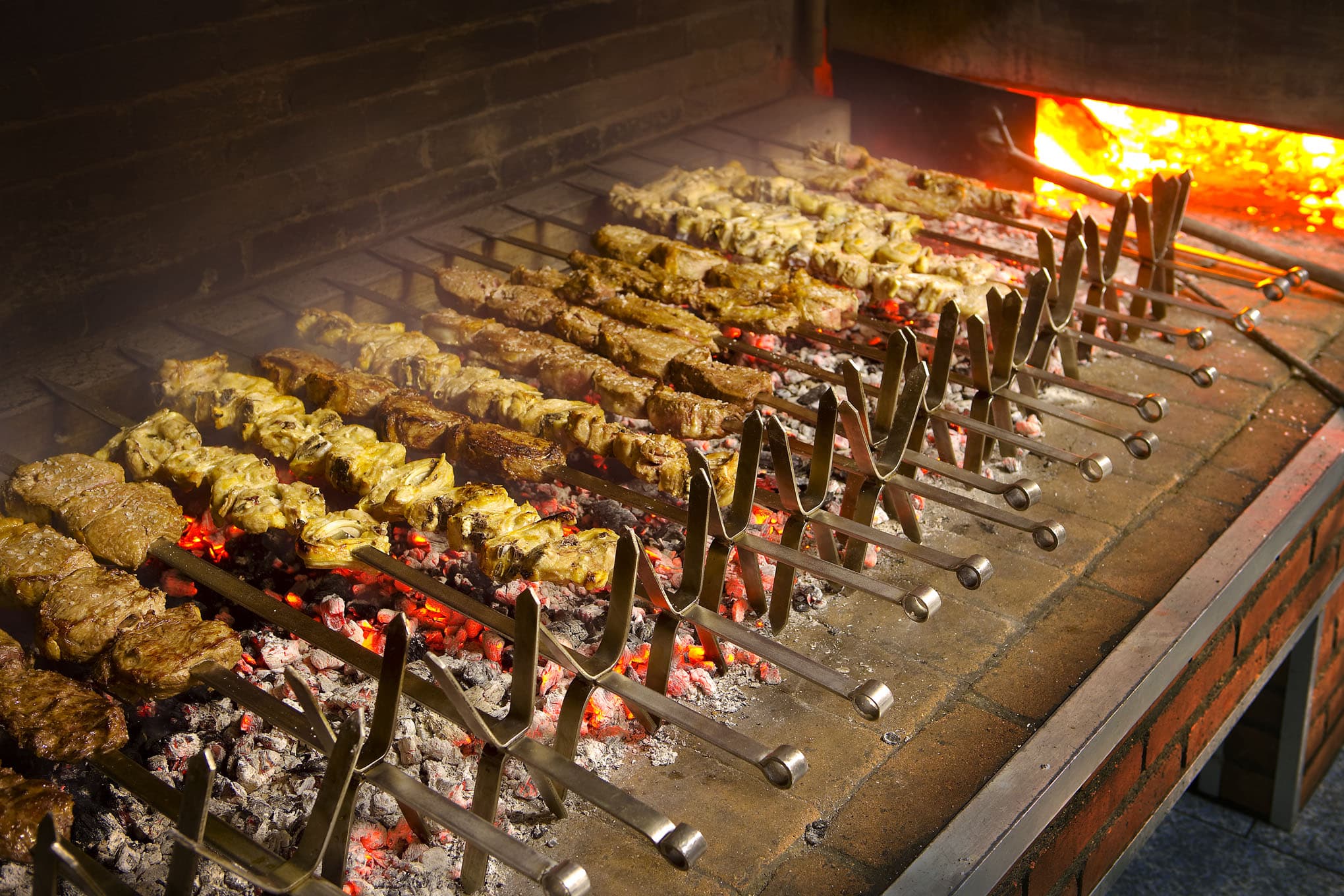 Asador tradicional con carnes y brochetas cocinándose sobre brasas ardientes en la Sierra de Francia.