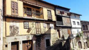 Fachadas coloniales de piedra y madera en Mogarraz, pueblo medieval de la Sierra de Francia con balcones y ventanas tradicionales.