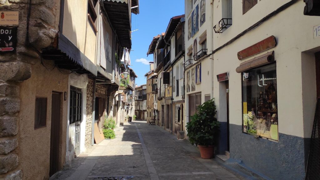 Calle empedrada de Mogarraz con casas blancas tradicionales, tiendas y arquitectura colonial de la Sierra de Francia.