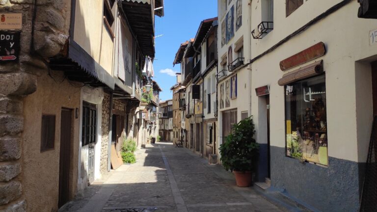 Calle empedrada de Mogarraz con casas blancas tradicionales, tiendas y arquitectura colonial de la Sierra de Francia.