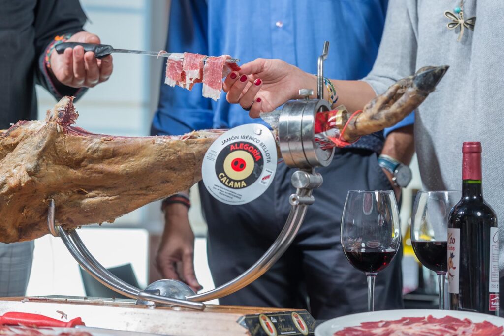 Degustación de Jamón Ibérico Alegría Cálama con vino tinto, mostrando corte tradicional en la Sierra de Francia.