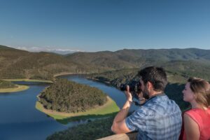 Joven fotografiando meandro del río Melero en la Sierra de Francia, rodeado de bosques y montañas nevadas al fondo.