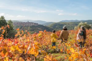 Familia disfrutando otoño entre viñedos coloridos de la Sierra de Francia con pueblo medieval al fondo