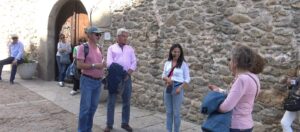 Grupo de turistas escucha guía turística frente a puerta medieval de piedra en la Sierra de Francia.