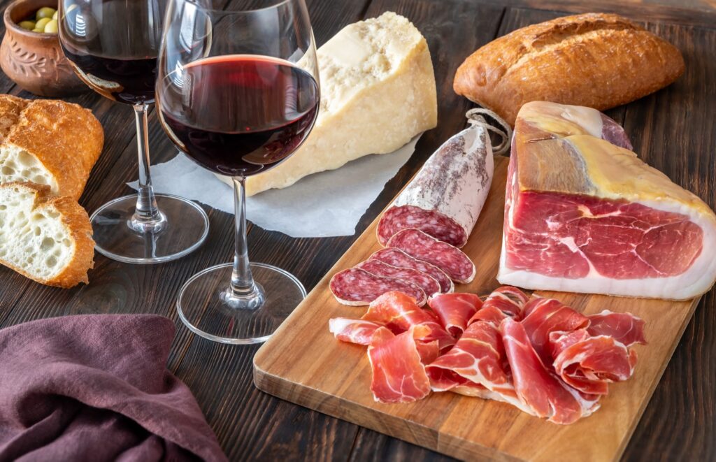 Tabla de embutidos, jamón ibérico y queso artesanal acompañados de vino tinto y pan tostado