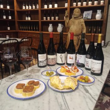 Degustación de vinos y tapas tradicionales en bodega de la Sierra de Francia con estatua decorativa.