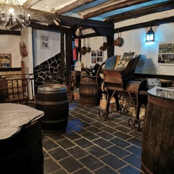Bodega tradicional de la Sierra de Francia con barriles de madera, vigas oscuras y decoración rústica de cuarta generación.