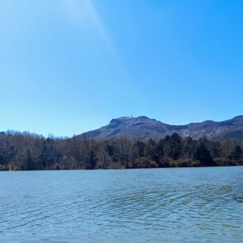 Lago tranquilo rodeado de montañas boscosas y cielo azul en la Sierra de Francia