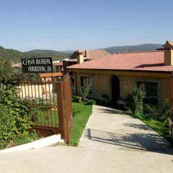 Casa Rural Arroal en la Sierra de Francia, construcción tradicional con tejado de barro y entrada rústica rodeada de vegetación.