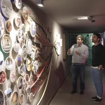 Tres visitantes observan una exposición interactiva con platos decorativos iluminados en el Centro de Interpretación de la Biosfera.