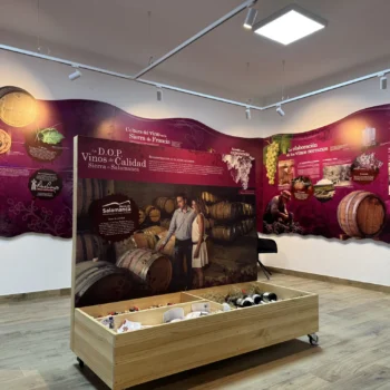 Exposición sobre cultura del vino en Sierra de Francia con barriles de roble y paneles informativos en tonos burgundy.