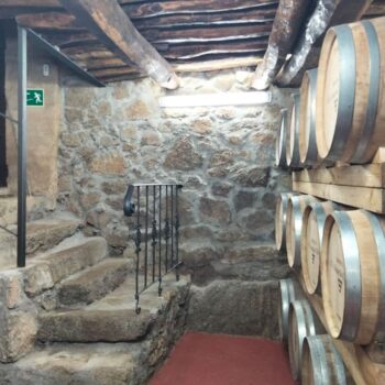 Bodega tradicional con barriles de vino, vigas de madera y paredes de piedra en la Sierra de Francia.