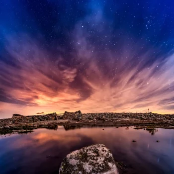 Atardecer estrellado sobre laguna con rocas musgo en paisaje montañoso de la Sierra de Francia