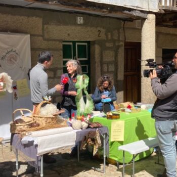 Demostración tradicional de hilado en la Sierra de Francia con artesanas, videógrafos y visitantes alrededor de una mesa con materiales artesanales.