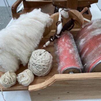 Rueca tradicional con lana blanca, ovillos y cardadores rojo para hilar en la Sierra de Francia.