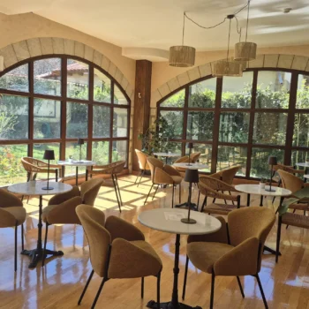Salón luminoso del Hotel Antiguas Eras con amplios ventanales, sillas mustaza y vistas a la Sierra de Francia.