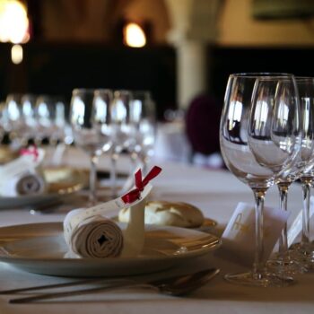 Mesa elegante de comedor con copas de vino, platos y servilletas decoradas para cena formal en hotel.