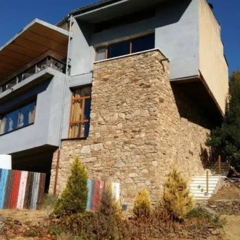 Casa de arquitectura moderna en la Sierra de Francia con fachada blanca, piedra natural y balcones de madera.