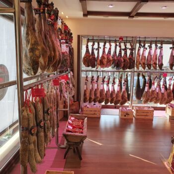 Tienda de jamones ibéricos colgados en vitrinas de refrigeración, productos artesanales de la Sierra de Francia.