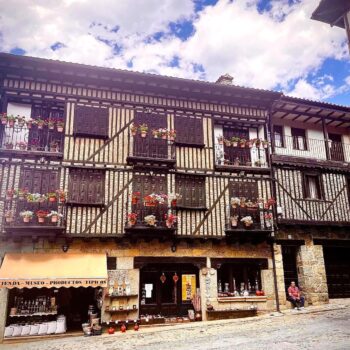 Casa tradicional de La Alberca con fachada de entramado de madera, balcones floridos y tienda de productos típicos en planta baja.