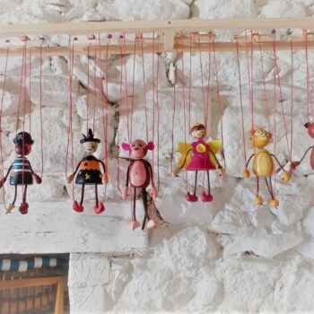 Maguetas artesanales colgantes coloridas expuestas en pared blanca rústica de la Sierra de Francia.