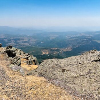 Vista panorámica desde la Peña de Francia con valle verde, pueblos dispersos y montañas al fondo bajo cielo despejado.