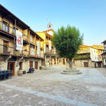 Plaza Mayor colonial con balconajes de madera, fachadas de piedra y decoraciones florales tradicionales en la Sierra de Francia.