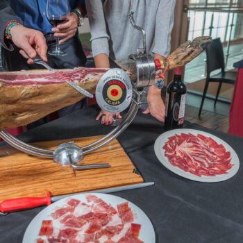 Degustación de jamón ibérico Salama con cortador tradicional, vino y platos de embutido en evento gastronómico