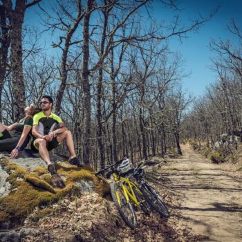 Ciclistas descansando en ruta de montaña con bosque de encinas y sendero de tierra en la Sierra de Francia