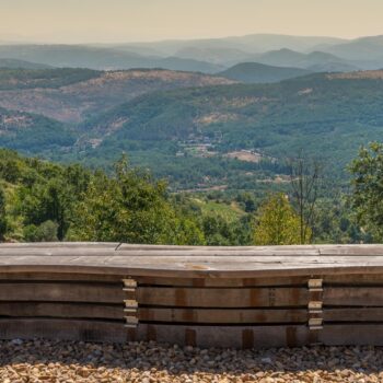 Vistas panorámicas de la Sierra de Francia desde mirador con barandilla de madera, valle verde y montañas al fondo.