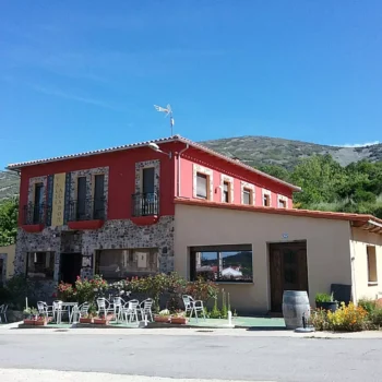 Restaurante hotel rural con arquitectura típica de piedra y tejadilla roja en la Sierra de Francia, con terraza y flores.