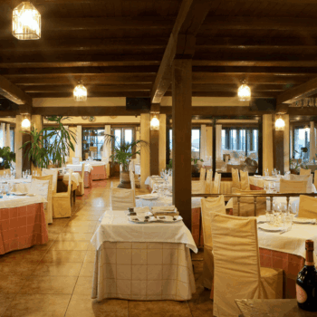 Elegante comedor del Restaurante Mirasierra con mesas redondas, sillas doradas y vistas panorámicas de la Sierra de Francia.