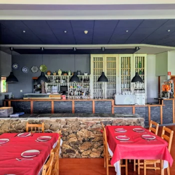 Interior de restaurante con mesas rojas, bar de piedra y madera, decoración tradicional en Sierra de Francia