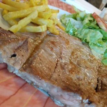 Jugoso filete a la parrilla con papas fritas y ensalada fresca en Restaurante de Arriba