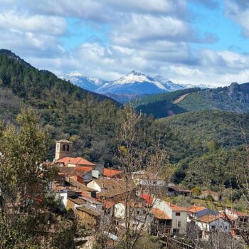 Pueblo blanco de San Esteban de la Sierra con iglesia, rodeado de bosques y montañas nevadas al fondo en la Sierra de Francia.