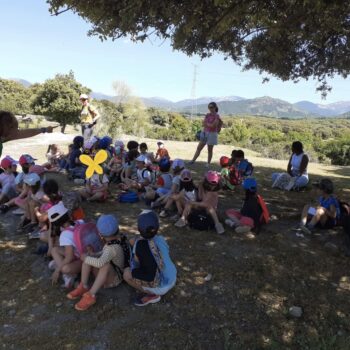 Grupo de niños en círculo durante actividad educativa en la Sierra de Francia, con montañas de fondo.