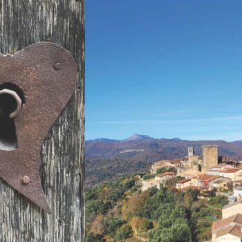 Cerradura de hierro en forma de corazón en madera antigua con vistas a pueblo medieval de la Sierra de Francia